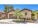 Tan single-story house with a brown garage door, well manicured yard and greenery at 35 Glade Water Dr, Henderson, NV 89052