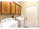 Practical laundry area features wooden cabinets above a washer and dryer and a white door at 35 Glade Water Dr, Henderson, NV 89052