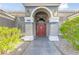 Inviting front entrance with a red door, stone archway, and manicured landscaping, creating a warm welcome at 3684 Mooncrest Cir, Las Vegas, NV 89129
