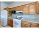Cozy kitchen features wood cabinetry, granite counters, and white appliances including a microwave and fridge at 3684 Mooncrest Cir, Las Vegas, NV 89129