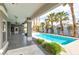 Covered patio overlooking a sparkling pool and lush landscaping with palm trees at 3684 Mooncrest Cir, Las Vegas, NV 89129