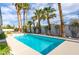 Private in-ground pool surrounded by lush landscaping and mature palm trees at 3684 Mooncrest Cir, Las Vegas, NV 89129