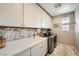 Well-lit laundry room features modern washer and dryer, white cabinets, and stylish floral backsplash at 421 Malpaso St, Las Vegas, NV 89138