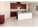 Open floor plan with kitchen island, brown cabinetry, tile floors, and granite countertops at 4274 Tarim St, Las Vegas, NV 89147