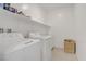 Well-lit laundry room with a washer, dryer, shelves, and a woven basket at 4436 Mural Glen Ct, North Las Vegas, NV 89084