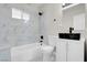 Bathroom featuring modern fixtures, black and white marble-style wall tiles, and a built-in tub at 5867 Bunch St, Las Vegas, NV 89122