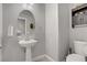 Elegant powder room featuring pedestal sink, decorative mirror, and updated fixtures and toilet at 626 Taliput Palm Pl, Henderson, NV 89011
