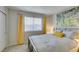 Bedroom featuring neutral carpet, grey walls, a large window with yellow curtains, and an eye-catching art piece at 7409 Central Butte Ave, Las Vegas, NV 89129