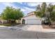 Inviting home featuring an arched entryway, a two-car garage, desert landscaping, and a well-maintained yard at 7409 Central Butte Ave, Las Vegas, NV 89129