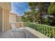 A serene balcony featuring white patio chairs, overlooking lush greenery and mature trees at 8221 Crow Valley Ln, Las Vegas, NV 89113