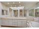 Bright bathroom with double vanity, soaking tub, decorative tile details, and large mirrors at 8221 Crow Valley Ln, Las Vegas, NV 89113