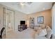 A cozy bedroom with a couch, TV, bookshelf, and a ceiling fan with a light at 8221 Crow Valley Ln, Las Vegas, NV 89113