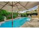 Backyard pool featuring a tranquil waterfall feature, mature landscaping, and poolside seating at 8221 Crow Valley Ln, Las Vegas, NV 89113