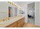 Bathroom with a dual sink vanity with a large mirror, wood cabinets, and a doorway to a bedroom at 8838 Spanish Mountain Dr, Las Vegas, NV 89148