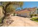 Large driveway leading to a three-car garage, surrounded by lush landscaping and mature trees at 8838 Spanish Mountain Dr, Las Vegas, NV 89148