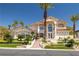 Elegant stucco home featuring a tile roof, lush landscaping, and a grand entrance with steps and tropical trees at 8838 Spanish Mountain Dr, Las Vegas, NV 89148