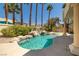 This home features a backyard pool with a waterfall, palm trees, lush landscaping and a covered patio area at 8838 Spanish Mountain Dr, Las Vegas, NV 89148