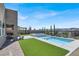 Backyard showcases a contemporary pool, spa, artificial turf, and brick-paved outdoor seating area at 9 Reverie Heights Ave, Henderson, NV 89011