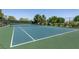 Well-maintained tennis court with net surrounded by mature trees and green fencing at 9001 Picket Fence Ave, Las Vegas, NV 89143