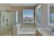 Well-lit bathroom with a glass shower, soaking tub, and view of the outdoors at 9335 Tonkawa Ave, Las Vegas, NV 89178