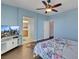 Bedroom with light-blue walls, ceiling fan, floral bedding, hard wood flooring, and a TV set at 9335 Tonkawa Ave, Las Vegas, NV 89178