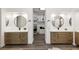 Modern bathroom featuring dual sinks, wood cabinets, round mirrors, and a walk-in closet at 9421 Queen Charlotte Dr, Las Vegas, NV 89145