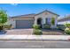 Charming single-story home with a tile roof, landscaped yard, and brick-paved driveway leading to a two-car garage at 9431 S Tee Pee Ln, Las Vegas, NV 89178