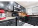 Well-lit kitchen featuring black cabinetry, granite countertops, stainless steel appliances and mosaic tile backsplash at 10143 Canyon Hills Ave, Las Vegas, NV 89148