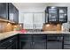 Bright kitchen featuring black cabinetry, granite countertops, stainless steel sink and mosaic tile backsplash at 10143 Canyon Hills Ave, Las Vegas, NV 89148