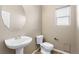 Powder room with modern pedestal sink, toilet, and window providing natural light at 10276 Cherry Brook St, Las Vegas, NV 89183