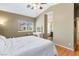 Well-lit bedroom with wood floors, a plush bed, vanity, and a glimpse into the en-suite bathroom, offering comfort and convenience at 10276 Cherry Brook St, Las Vegas, NV 89183