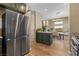 Modern kitchen with stainless steel fridge, an island and dining area with granite countertops and green cabinets at 10276 Cherry Brook St, Las Vegas, NV 89183