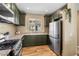 This is a kitchen featuring stainless steel appliances, wood floors, granite counters, and dark green cabinetry at 10276 Cherry Brook St, Las Vegas, NV 89183