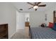 Bedroom showcasing a wooden bed, ceiling fan, and access to the bathroom area with carpeted floor at 11944 Dolcemente Ln, Las Vegas, NV 89138