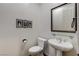 Powder room featuring a pedestal sink, decorative mirror and artwork, and a toilet with accessories at 1637 Wellington Springs Ave, Henderson, NV 89052