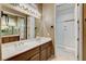 Bright bathroom featuring a double sink vanity with wood cabinets and a separate glass-enclosed shower at 1637 Wellington Springs Ave, Henderson, NV 89052