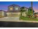 Two-story home with a three-car garage, well-manicured lawn, and mature trees at dusk at 193 Jeri Dr, Henderson, NV 89074