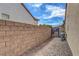 Long narrow side yard with stone wall, decorative stone, and brick pavers leading to backyard access at 2092 Wildwood Lake Street, Henderson, NV 89052