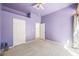 An airy bedroom with lilac walls, carpet flooring, and access to a private balcony at 2097 Eaglepath Cir, Henderson, NV 89074