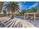 The backyard features a pool, a large palm tree, pergola, patio and a wooden fence at 2129 N Michael Way, Las Vegas, NV 89108