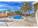 A backyard pool with a wooden fence and a large palm tree under a blue sky at 2129 N Michael Way, Las Vegas, NV 89108