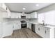 Modern kitchen with white cabinetry, stainless steel appliances, and gray wood-look floors at 2346 Roan Ave, Las Vegas, NV 89119