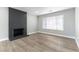 View of a bright living room with wood-look floors, a decorative fireplace, and a large window at 2346 Roan Ave, Las Vegas, NV 89119
