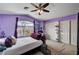 Cozy bedroom with purple walls, a ceiling fan, a large window with palm tree views, and a closet at 3055 Whispering Crest Dr, Henderson, NV 89052