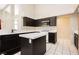 Bright kitchen featuring an island, white tile floors, and black cabinets at 3630 Daisy Field Dr, North Las Vegas, NV 89032