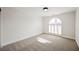 Empty bedroom with neutral carpet, white walls, and an arched window with shutters at 5840 N El Capitan Way, Las Vegas, NV 89149