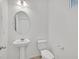 Well-lit powder room with pedestal sink, toilet, and a round mirror, offering a clean and functional space at 6130 Yuzu Pl, Las Vegas, NV 89122