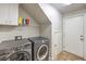 Convenient laundry room with modern washer and dryer, overhead storage, and tile flooring at 6546 American Flower St, Las Vegas, NV 89148
