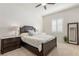Bedroom with a ceiling fan, a dark wooden bed frame, lamps, and window with plantation shutters at 7340 Orchard Harvest Ave, Las Vegas, NV 89131