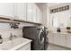 Laundry room with front loading washer and dryer, white cabinets, and utility sink at 7340 Orchard Harvest Ave, Las Vegas, NV 89131